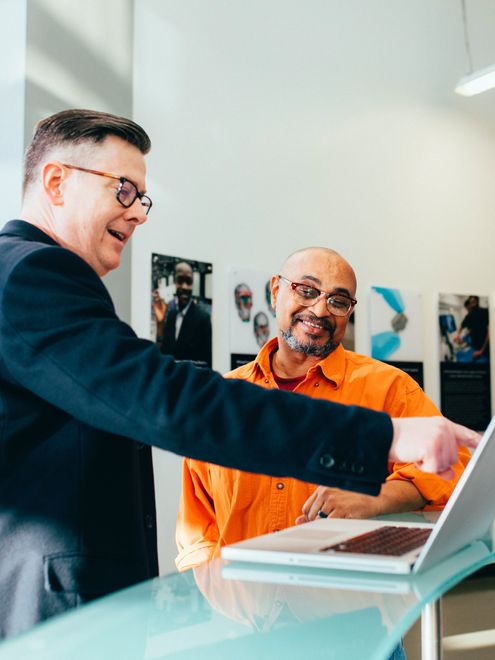 Two men pointing at computer